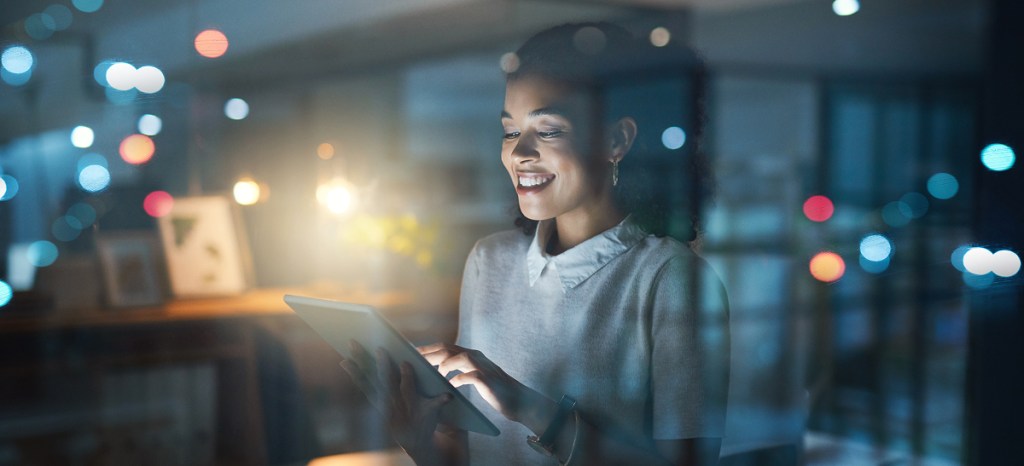 women on laptop with city lights in background